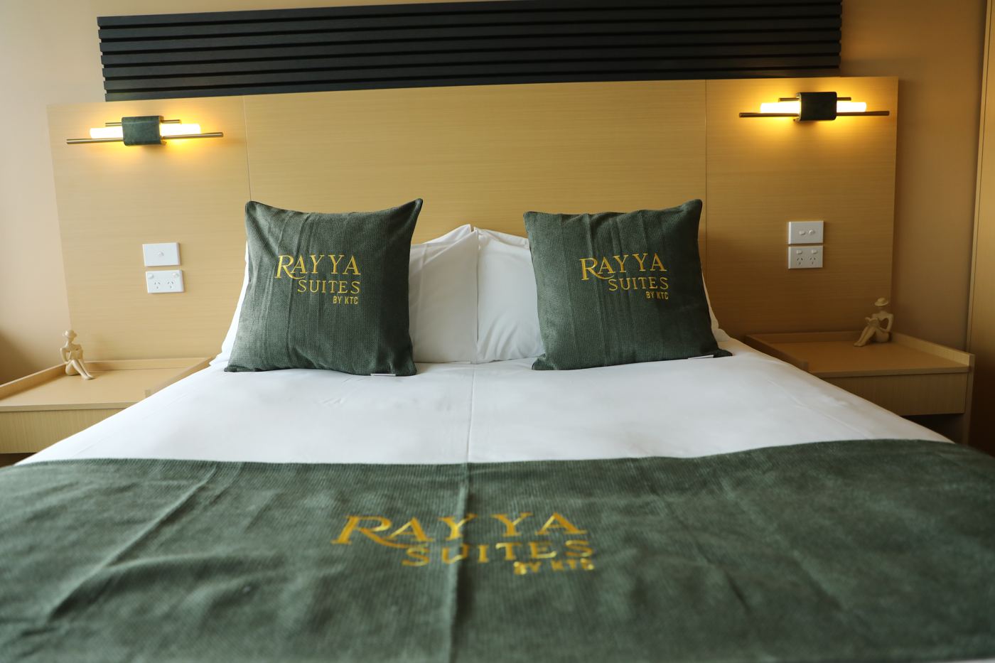 A Rayya Suites king room with forest-green bed runner and embroidered cushions